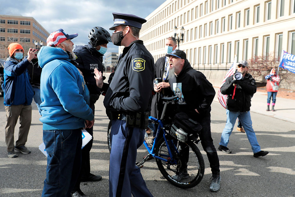 Michigan State Police in Lansing separate supporters of President Donald Trump and a supporter of President-elect Joe Biden Nov. 23 as the Board of State Canvassers met to certify the results of the election. (CNS/Reuters/Rebecca Cook) Michigan State Police in Lansing separate supporters of President Donald Trump and a supporter of President-elect Joe Biden Nov. 23 as the Board of State Canvassers met to certify the results of the election. (CNS/Reuters/Rebecca Cook)