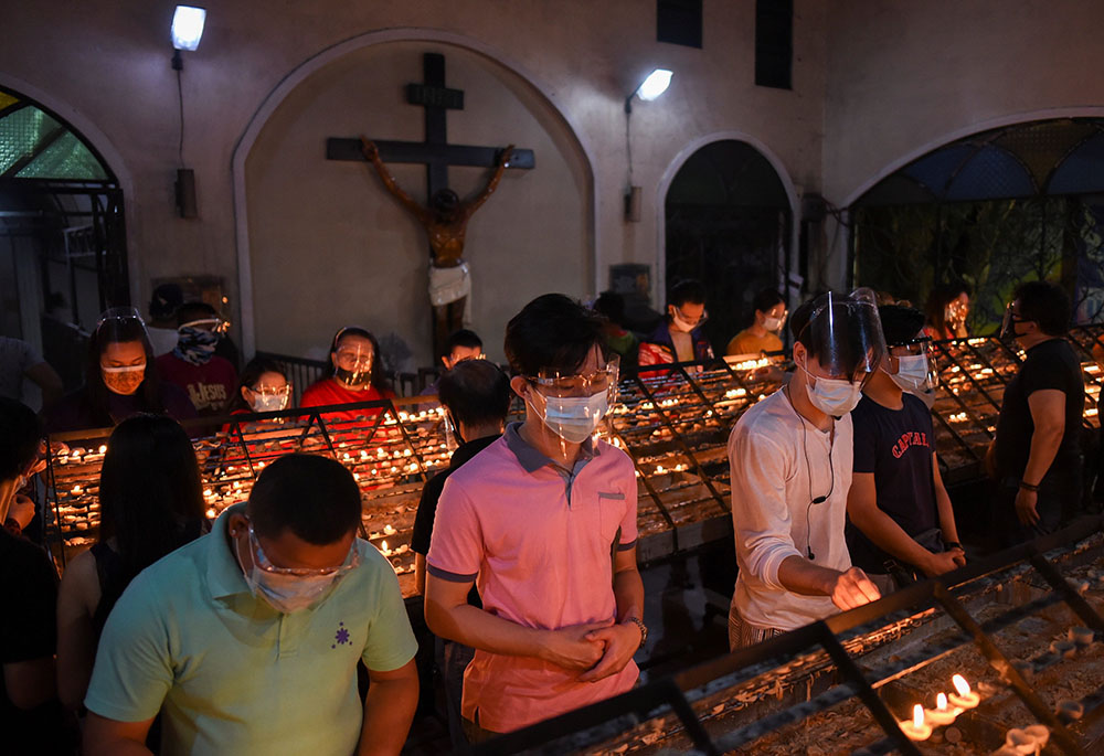 People wearing protective masks and face shields light candles after the first of the nine-day novena Masses for Simbang Gabi at the National Shrine of Our Mother of Perpetual Help in Manila, Philippines, Dec. 16, 2020. (CNS/Reuters/Lisa Marie David)