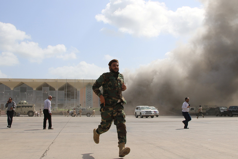 A security member runs during an attack on the airport in Aden, Yemen, Dec. 30, 2020, moments after a plane landed carrying a newly formed Cabinet for government-held parts of the country. (CNS/Fawaz Salman, Reuters)