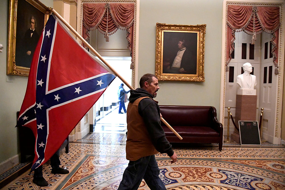 A supporter of President Donald Trump carries a Confederate battle flag on the second floor of the U.S. Capitol building in Washington near the entrance to the Senate after breaching security defenses Jan. 6. (CNS/Reuters/Mike Theiler)