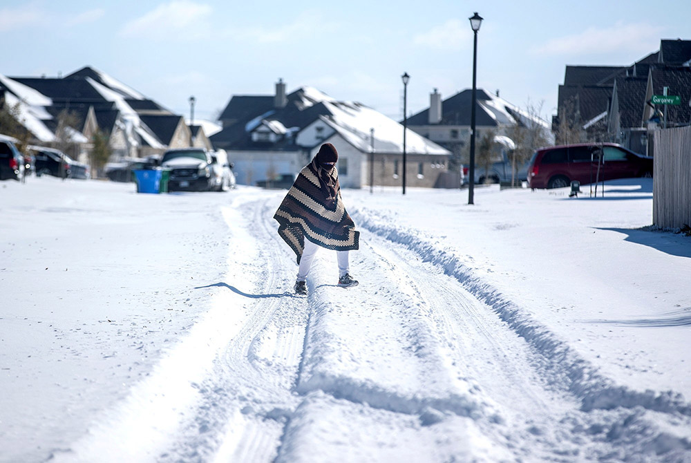 A man in Pflugerville, Texas, walks to his friend's house Feb. 15 in a neighborhood that had no electricity. (CNS/USA Today Network via Reuters/Austin American-Statesman/Bronte Wittpenn)