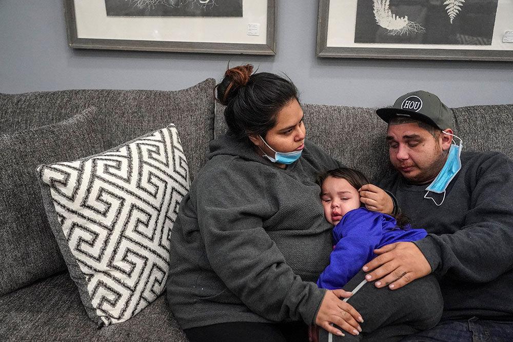 Patrick Youngblood and his wife, Marisol, comfort their daughter Audrey at Gallery Furniture store in Houston, which opened its doors as a warming station Feb. 17 after winter weather caused electricity blackouts throughout the state. (CNS/Reuters)