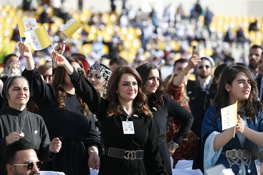 Women wave Vatican flags as they wait for Pope Francis to celebrate Mass at Franso Hariri Stadium in Irbil, Iraq, March 7. (CNS/Paul Haring)