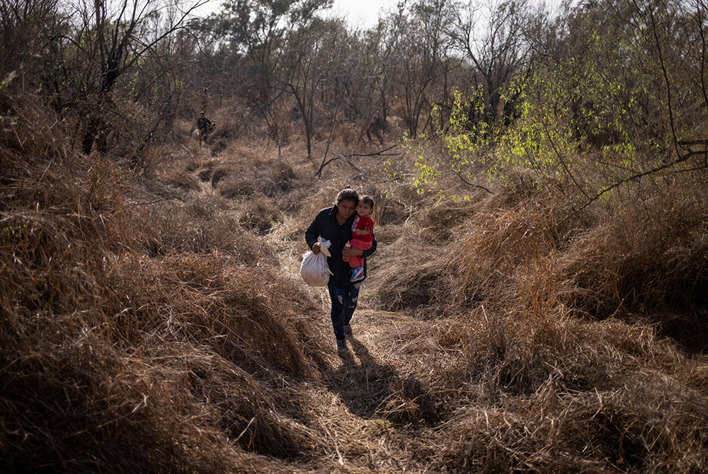 A Honduran migrant carries her baby into Penitas, Texas, after crossing the Rio Grande River from Mexico March 10. (CNS/Adrees Latif, Reuters)