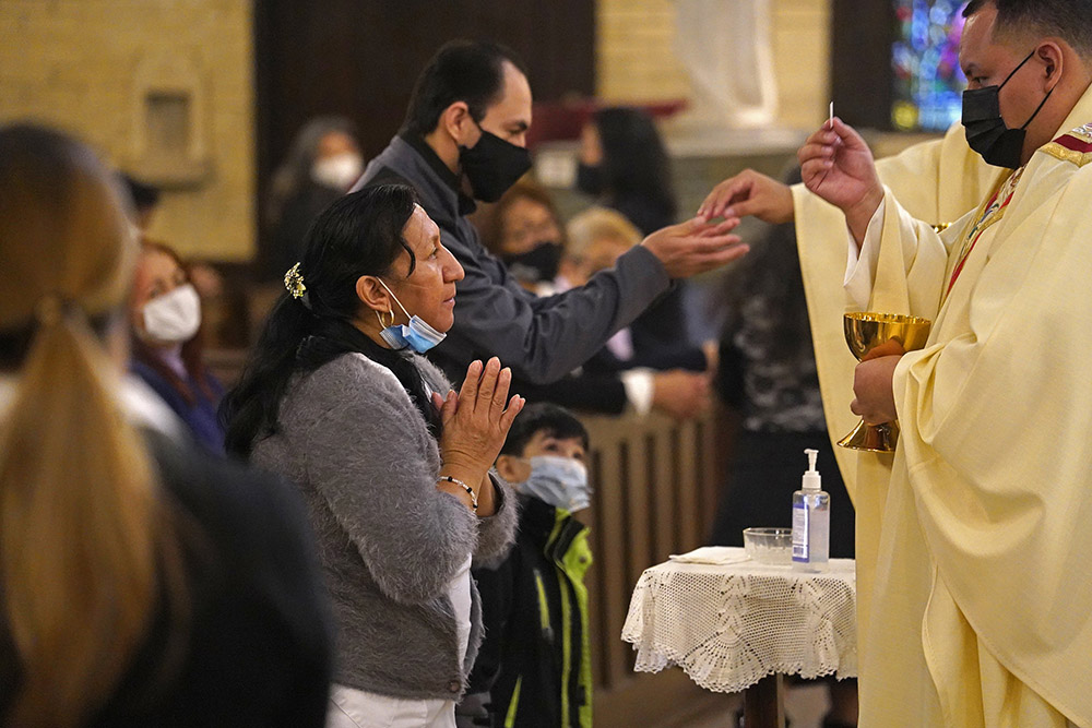 A woman receives Communion during a memorial Mass for Fr. Jorge Ortiz-Garay at St. Brigid Church in Brooklyn, New York, March 27, on the first anniversary of the priest's death from COVID-19.