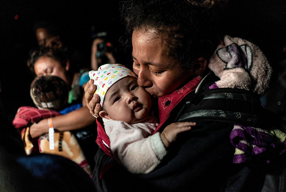A mother from Guatemala seeking asylum in the U.S. kisses her 3-month-old baby while waiting to be escorted by Border Patrol agents April 7 in Roma, Texas, after crossing the Rio Grande into the United States. (CNS/Reuters/Go Nakamura)