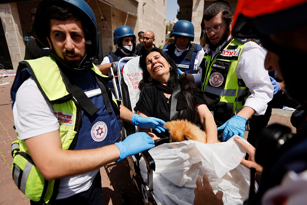 A woman holds her dog as she is evacuated by medics in Ashkelon, Israel, May 11, after being wounded from a rocket was launched from the Gaza Strip. (CNS/Reuters/Amir Cohen)