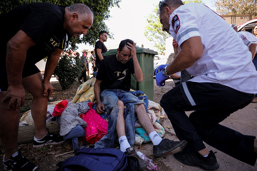 An Israeli medic treats a man who was wounded after a rocket launched from the Gaza Strip landed near homes in Moshav Zohar, Israel, May 13. (CNS/Reuters/Amir Cohen)