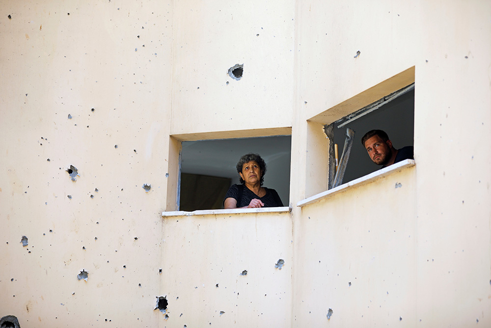 People look out May 20 in Petah Tikva, Israel, from a building damaged after a rocket fired from the Gaza Strip landed nearby. (CNS/Reuters/Nir Elias) People look out May 20 in Petah Tikva, Israel, from a building damaged after a rocket fired from the Gaza Strip landed nearby. (CNS/Reuters/Nir Elias)