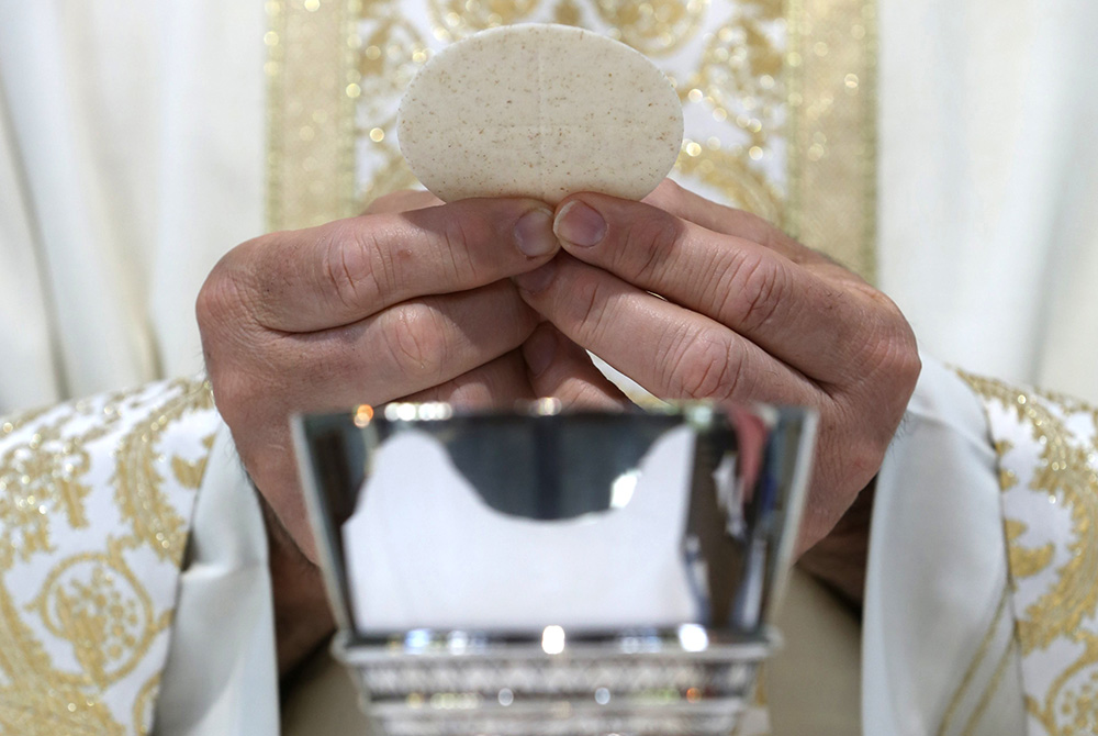 A priest holds the Eucharist in this illustration. (CNS/Bob Roller)