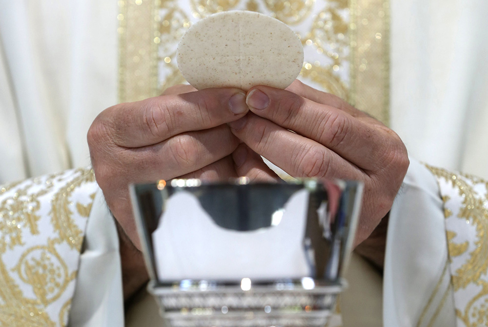 A priest holds the Eucharist in this illustration. (CNS/Bob Roller) A priest holds the Eucharist in this illustration. (CNS/Bob Roller)