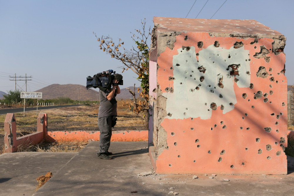 A cameraman takes video of a bullet-riddled chapel April 23 near Aguililla, Mexico. (CNS/Reuters/Alan Ortega)