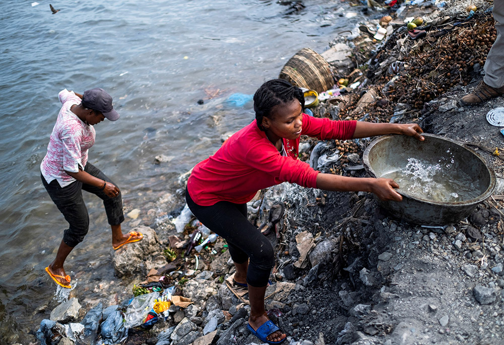 A woman collects water from a heavily polluted bay in Cap-Haitien, Haiti, July 21, 2021. As the poorest nation in the Western Hemisphere, Haiti has to deal with issues of poverty and water scarcity on a daily basis. (CNS/Reuters/Ricardo Arduengo)