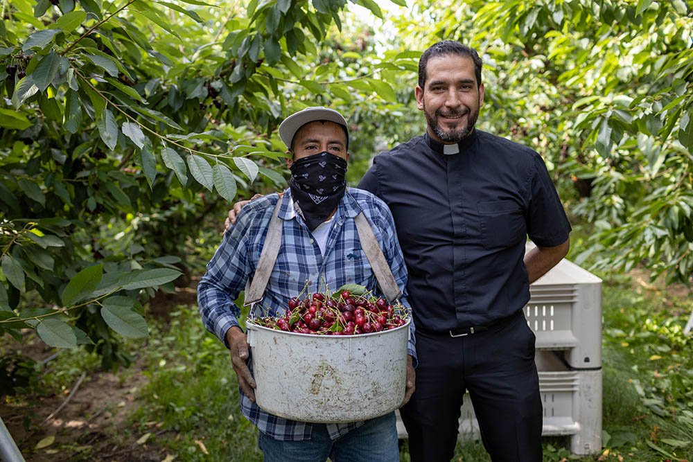 Fr. Jésus Mariscal, migrant ministry supervisor for the Diocese of Yakima, Washington, poses with one of the farmworkers in his ministry, along with his freshly picked crop on July 28. (Courtesy of Catholic Extension)