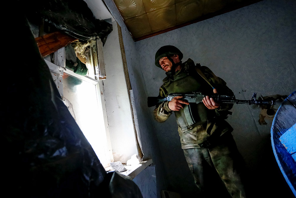 A militant of the self-proclaimed Luhansk People's Republic stands inside an abandoned house near fighting on the line of separation from the Ukrainian armed forces in Luhansk, Ukraine, July 16, 2021. (CNS/Reuters/Alexander Ermochenko)