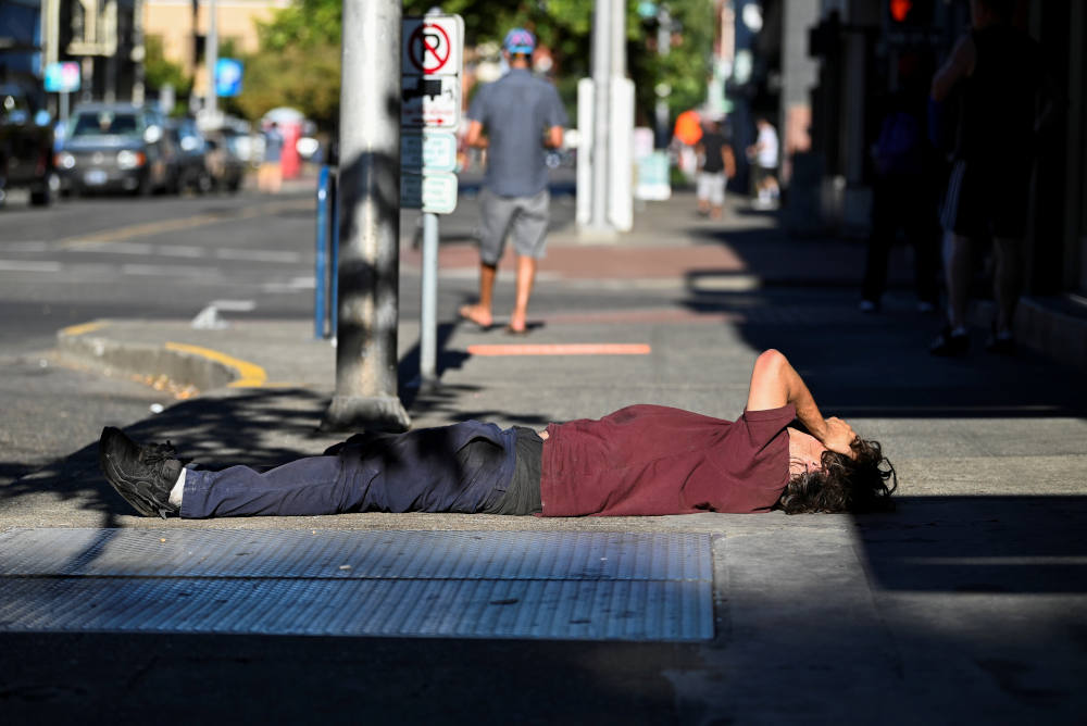 A man in Portland, Ore., lies on a sidewalk during a heatwave Aug. 11, 2021. (CNS photo/Mathieu Lewis-Rolland, Reuters)