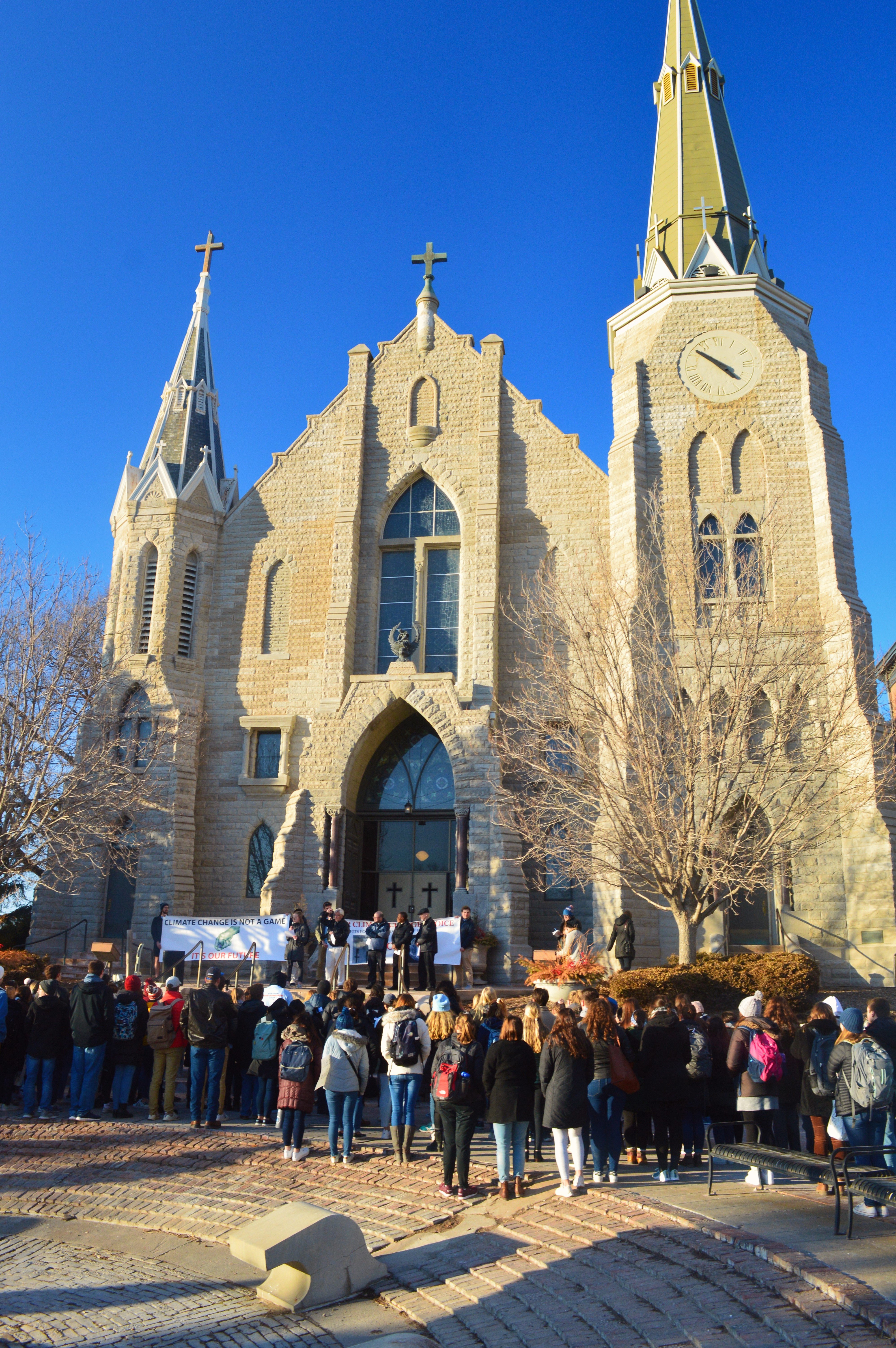 Students and others gather on the steps of St. John Church on the Creighton University campus in Omaha, Neb., Feb. 20, 2020, for a prayerful rally to call on school leaders to divest from fossil fuels. (CNS photo/courtesy Emily Burke)