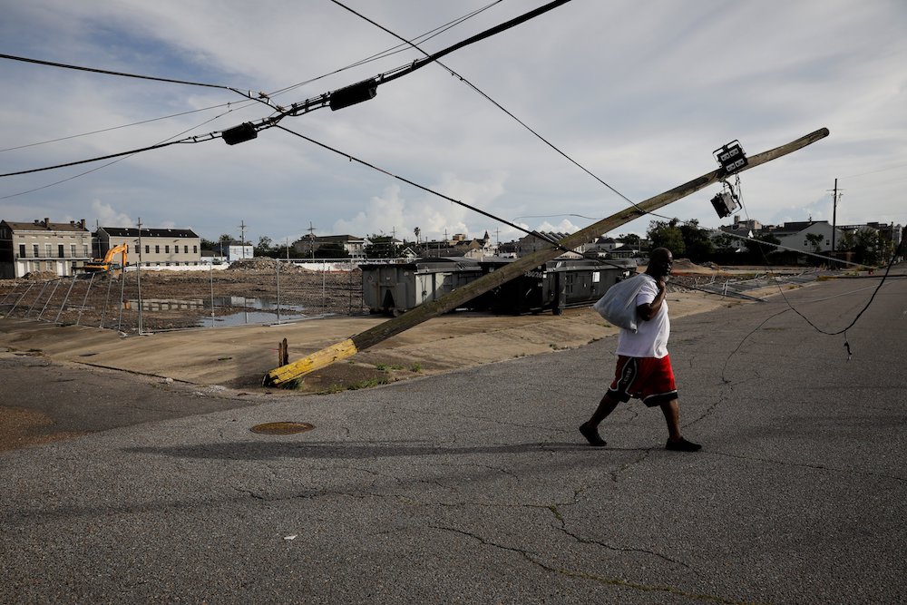A man in New Orleans walks past a damaged electric line Aug. 30, after Hurricane Ida made landfall. (CNS photo/Marco Bello, Reuters)