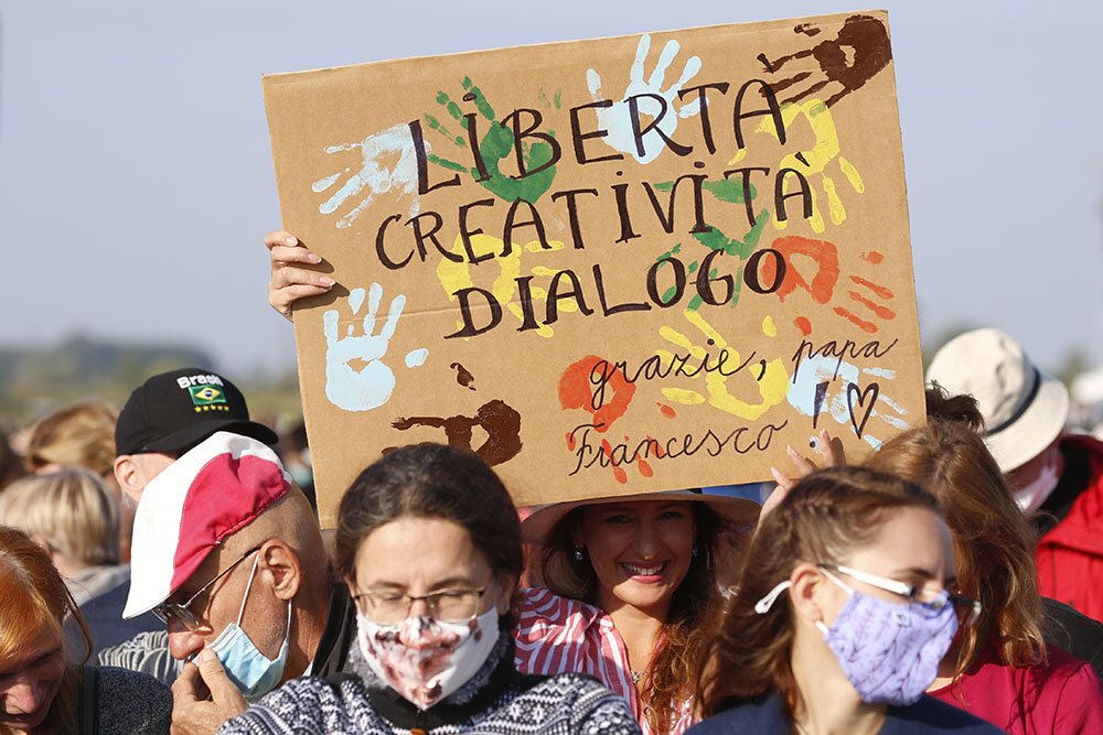 A woman holds a sign in Italian reading "Liberty, Creativity and Dialogue" as people wait for Pope Francis' arrival to celebrate Mass on the fields outside the Basilica of Our Lady of Seven Sorrows in Sastin, Slovakia, Sept. 15. (CNS/Paul Haring)