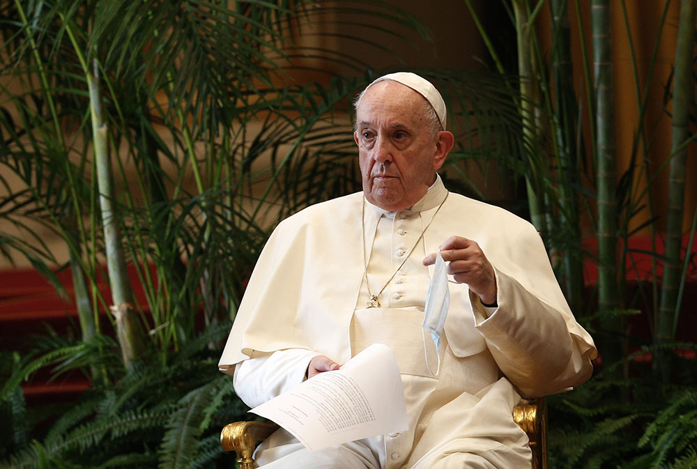 Pope Francis holds a text and his mask during a meeting on "Faith and Science: Towards COP26" with religious leaders in the Apostolic Palace at the Vatican Oct. 4, 2021. The meeting was part of the run-up to the U.N. Climate Change Conference in Glasgow.