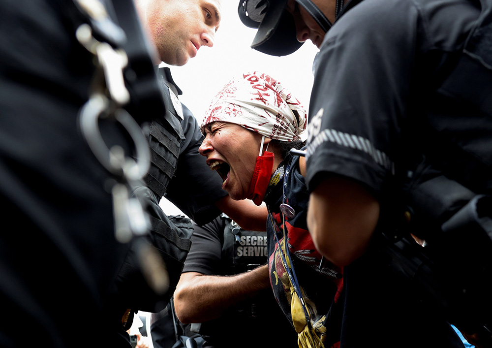 A demonstrator near the White House in Washington is arrested by U.S. Secret Service agents Oct. 11, during a climate change protest to mark Indigenous Peoples Day. (CNS/Reuters/Evelyn Hockstein)