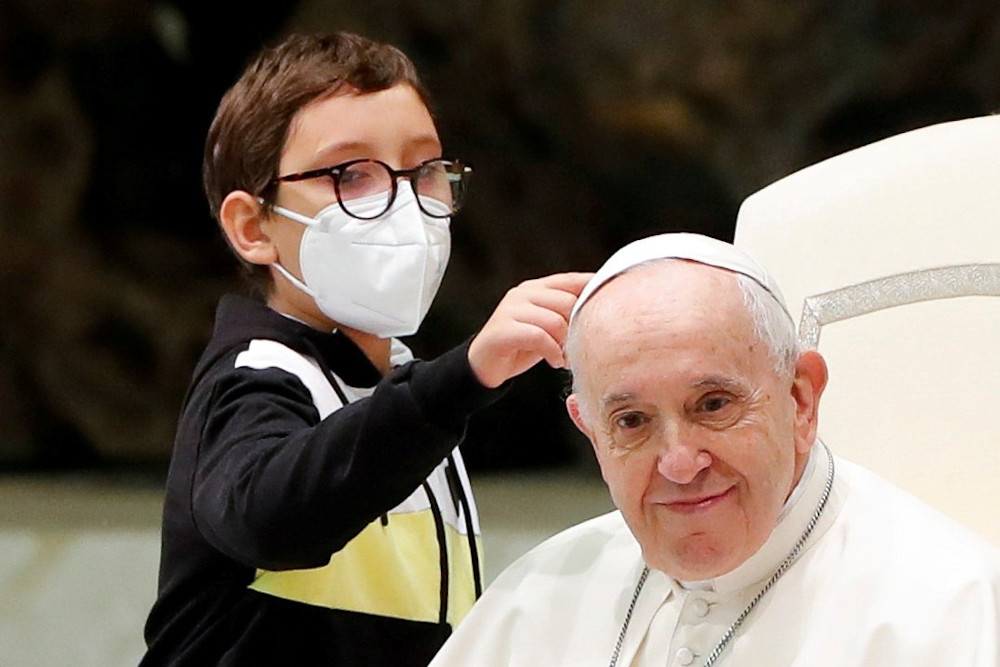 Ten-year-old Paolo touches Pope Francis' zucchetto after spontaneously walking onto the stage during the weekly general audience at the Vatican Oct. 20. (CNS/Reuters/Remo Casilli)