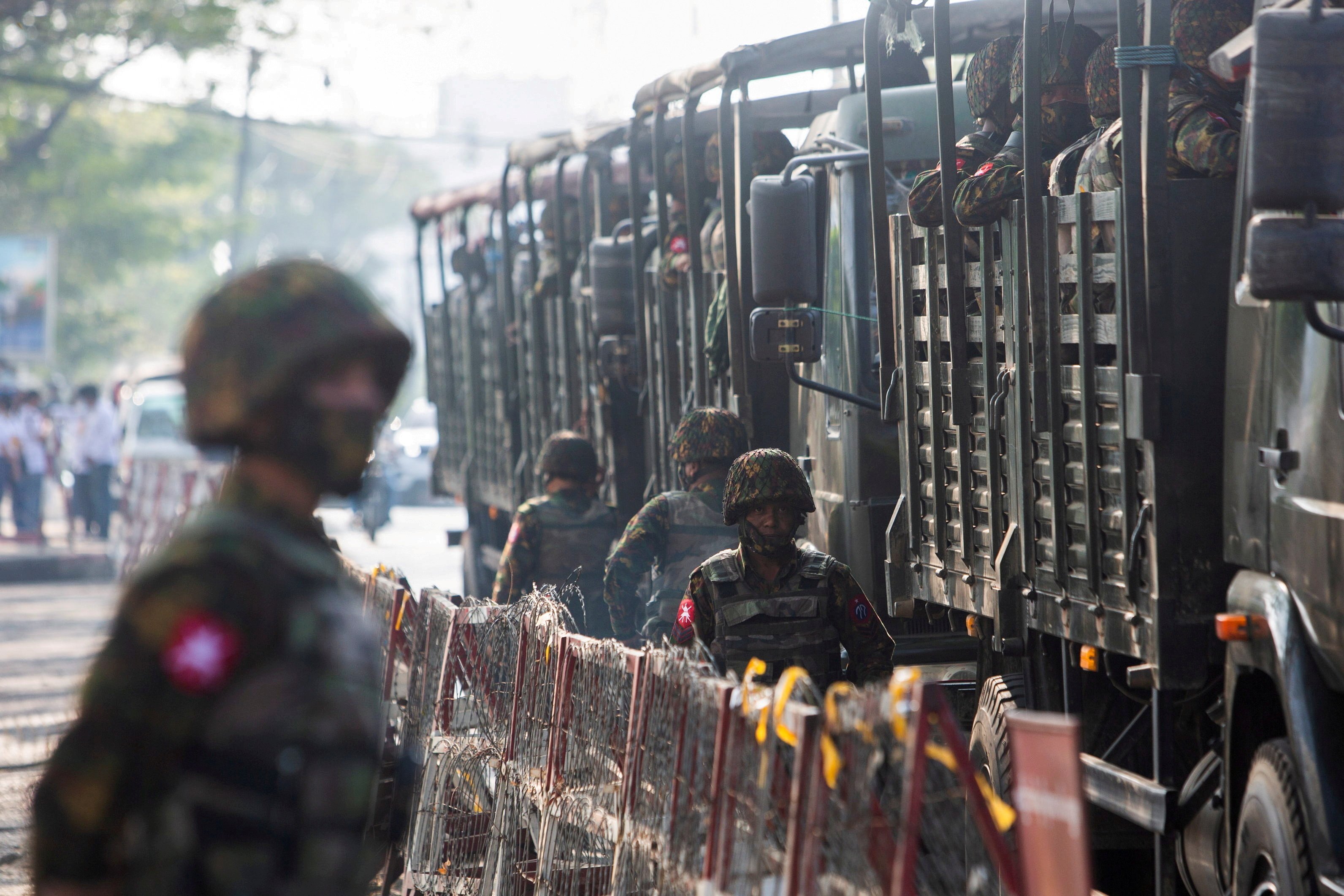 Soldiers stand next to military vehicles as people gather to protest the military coup in Yangon, Myanmar, Feb. 15, 2021. (CNS photo/Reuters)