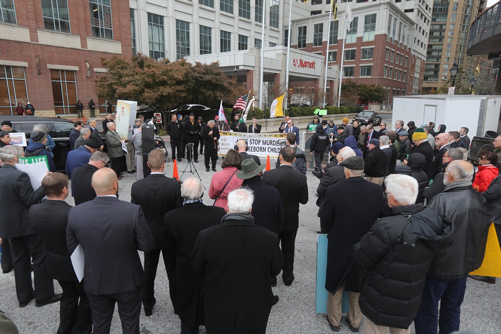 A clergyman leads a rosary with the National Men's March to End Abortion organizers Nov. 15, outside the hotel in Baltimore where the fall general assembly of the U.S. Conference of Catholic Bishops is being held Nov. 15-18. (CNS/Bob Roller)