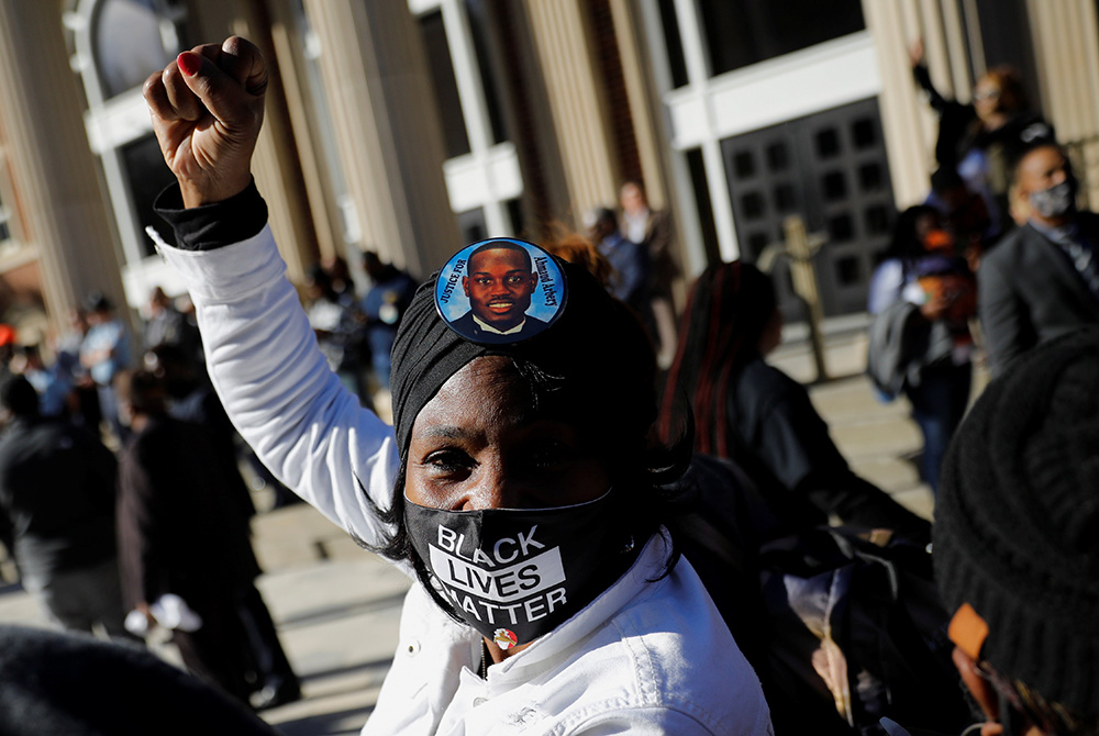 A woman outside the Glynn County Courthouse in Brunswick, Georgia, raises her fist Nov. 24, after the jury reached a guilty verdict in the trial of the men convicted of the February 2020 murder of 25-year-old Ahmaud Arbery. (CNS/Reuters/Marco Bello)