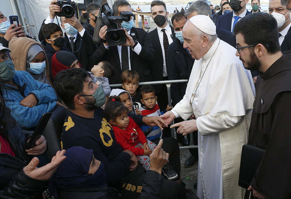 Pope Francis holds the hand of a man during a visit with refugees at the government-run Reception and Identification Center Dec. 5 in Mytilene, Greece. (CNS/Paul Haring)