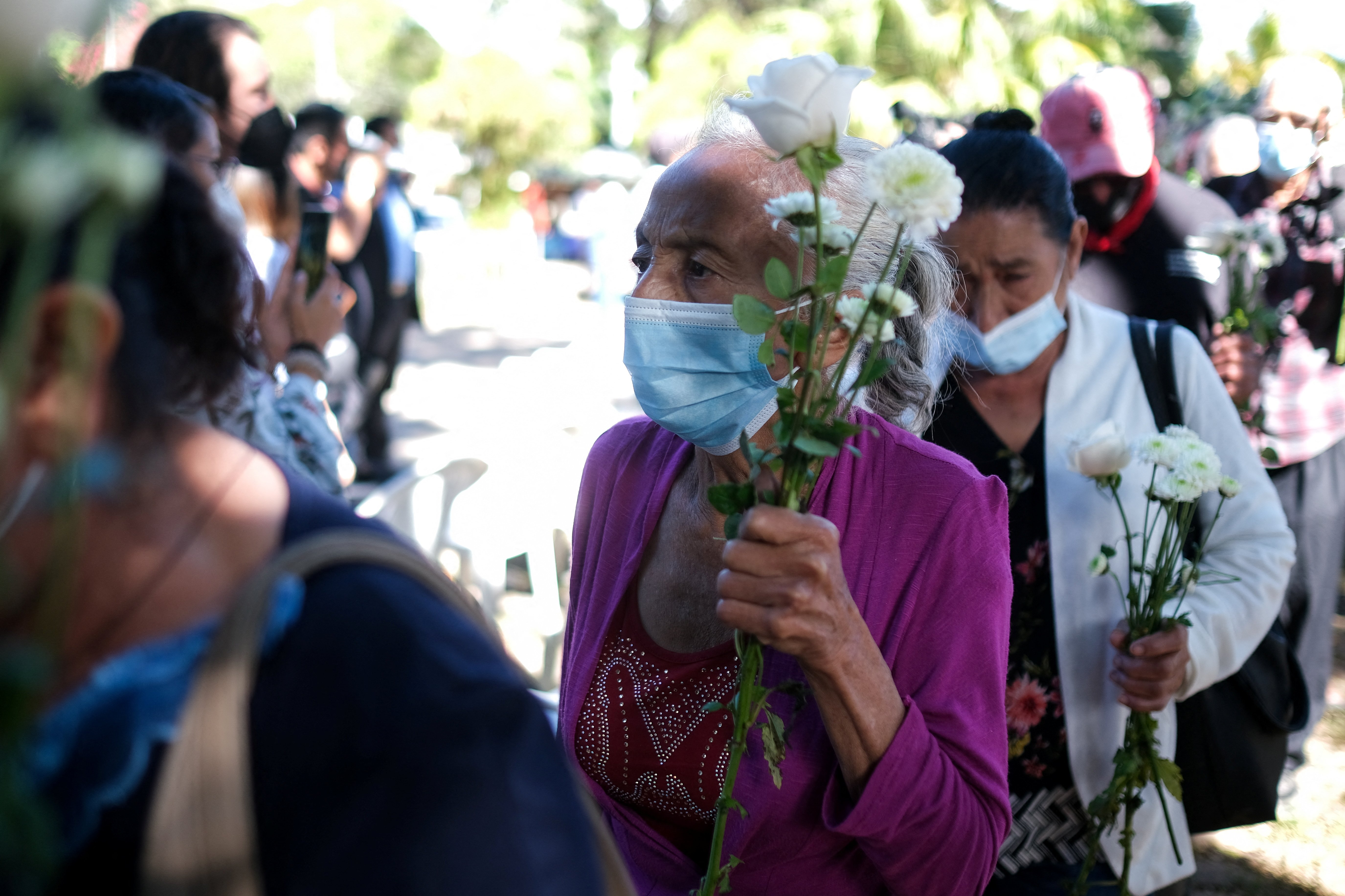 Women carry flowers as the arrive to take part in a ceremony to commemorate the 40th anniversary of the El Mozote massacre in El Salvador Dec. 11, 2021. (CNS photo/Jose Cabezas, Reuters)
