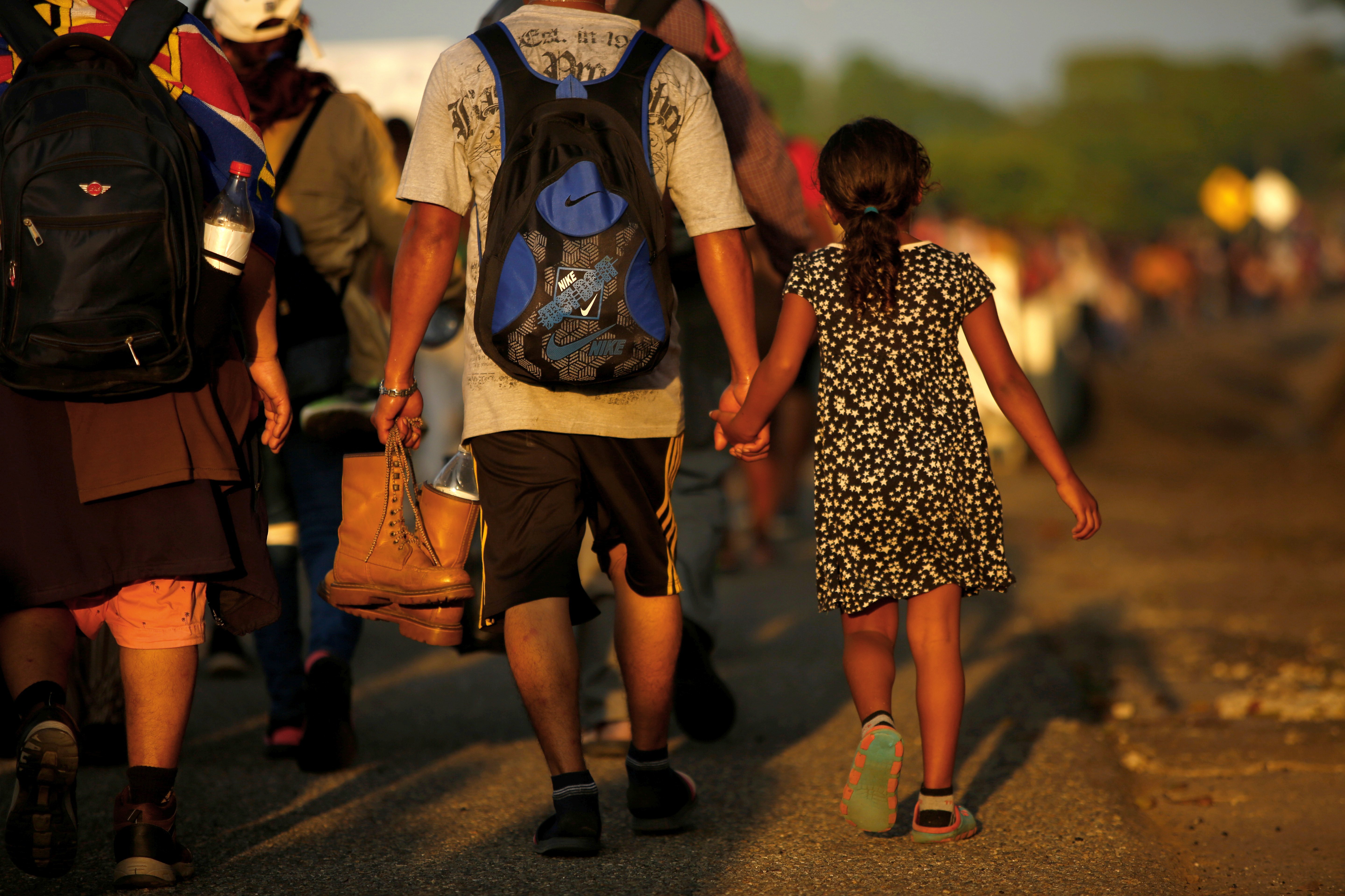 Jose Francisco from Honduras leads his 8-year-old daughter, Zuabelin, by the hand Nov. 22, 2021, as they took part in a caravan near Villa Mapastepec, Mexico, and headed to the U.S. border. (CNS photo/Jose Luis Gonzalez, Reuters)