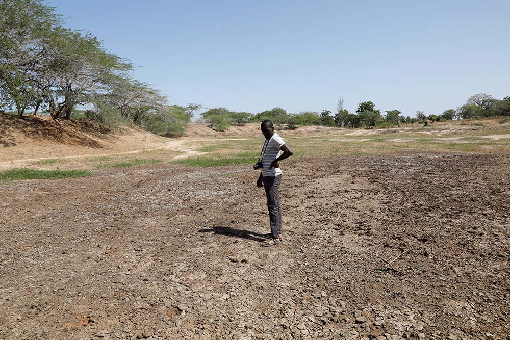 Scientist Chris Shitote examines a dry water hole in Kilifi, Kenya, Feb. 16. In recent years, nations have been quick to make pledges to confront climate change. Pledges, alas, need to be implemented and that has proven more difficult. (CNS/Reuters/Baz Ratner)