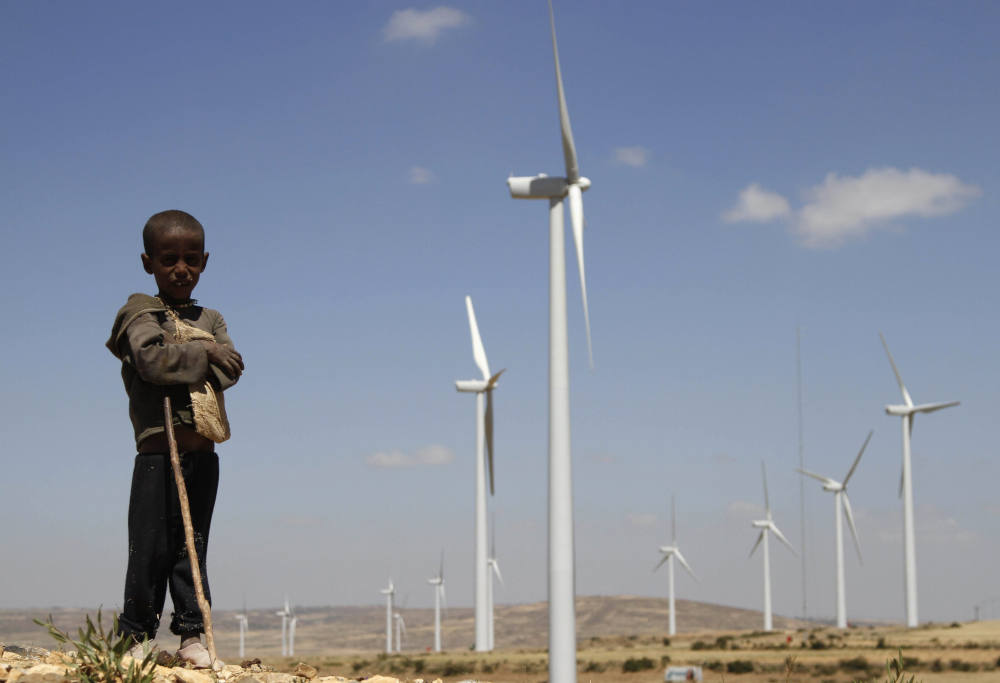 A boy is pictured in a file photo standing in front of wind turbines at the Ashegoda Wind Farm, near Mekele in Ethiopia's Tigray region. Congolese Cardinal Fridolin Ambongo Besungu said the climate crisis is holding back African development. (CNS photo/Kumerra Gemechu, Reuters)