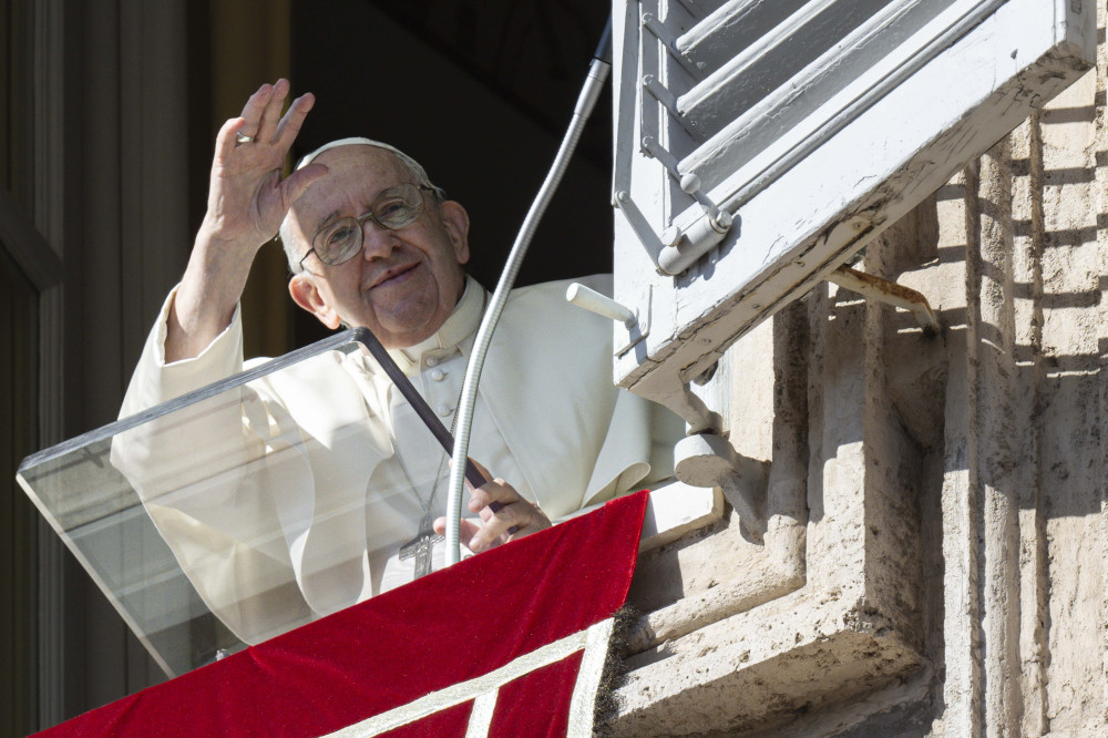 Pope Francis waves from the window of the papal apartment