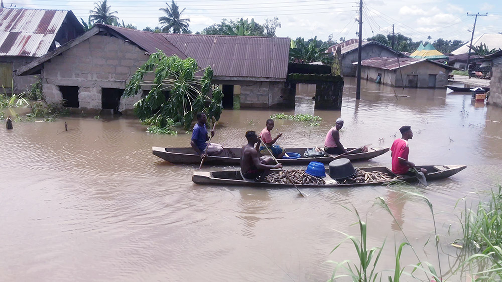 People transport cassava by canoe along flooded residential streets in Bayelsa, Nigeria, Oct. 20. (AP/Reed Joshua)