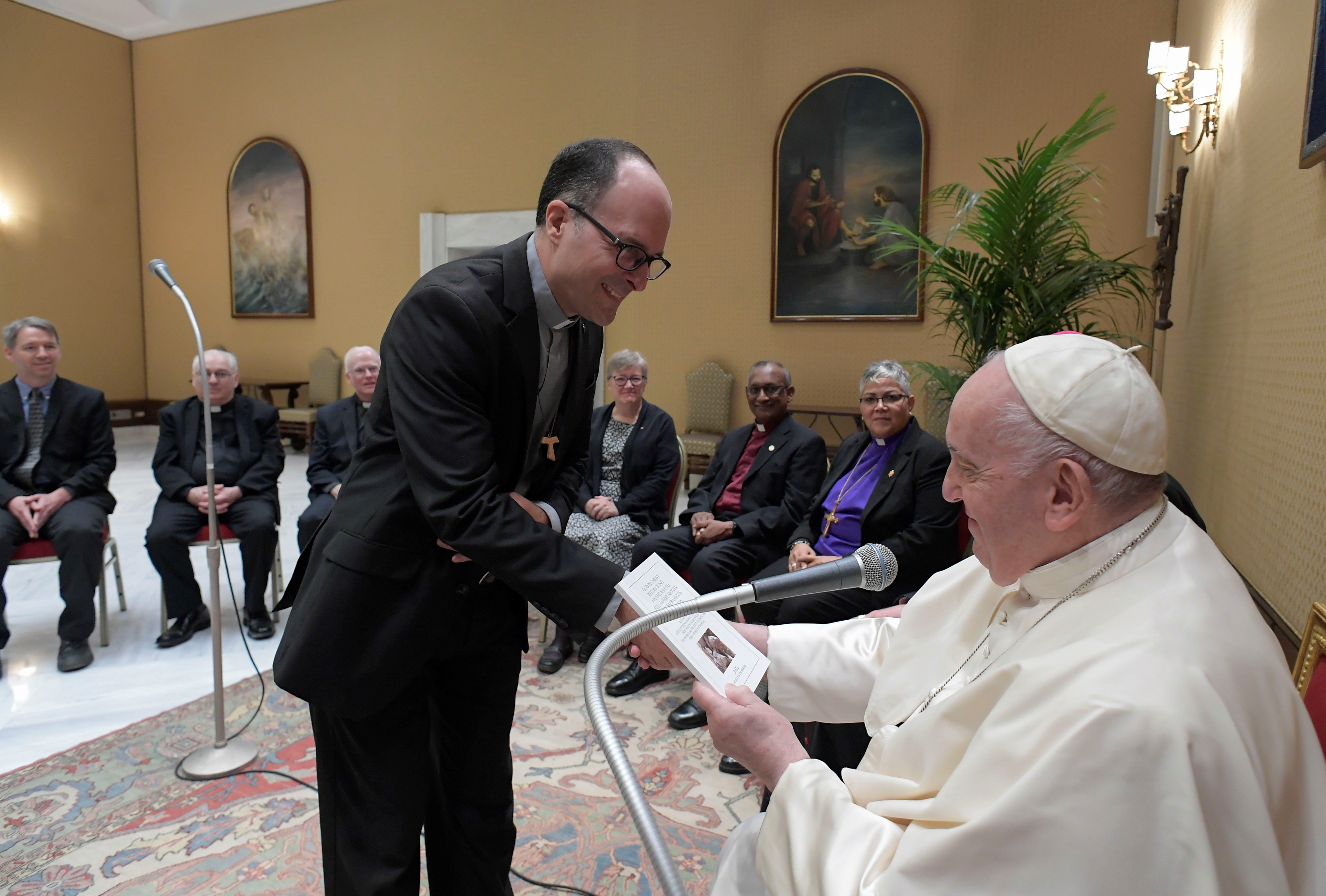 Man hands report to Pope Francis