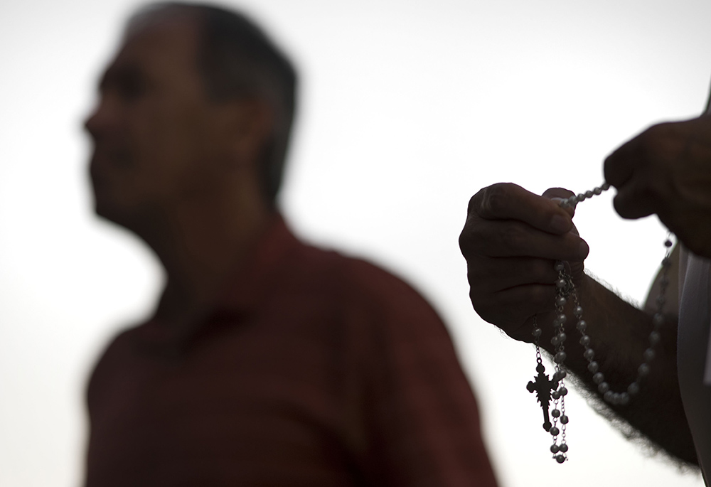 An attendee prays the rosary Oct. 1, 2018, during a public session on the issue of clergy sexual abuse at Our Mother of Confidence Parish Hall in San Diego. (CNS/David Maung)