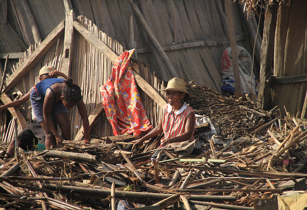 A Malagasy family is pictured outside their destroyed home Feb. 8 in Mananjary, Madagascar, in the aftermath of Cyclone Batsirai. Ahead of COP27, some organizations in Africa plan to call for compensation for the damage climate change has already exacerbated. (CNS/Courtesy of CRS)