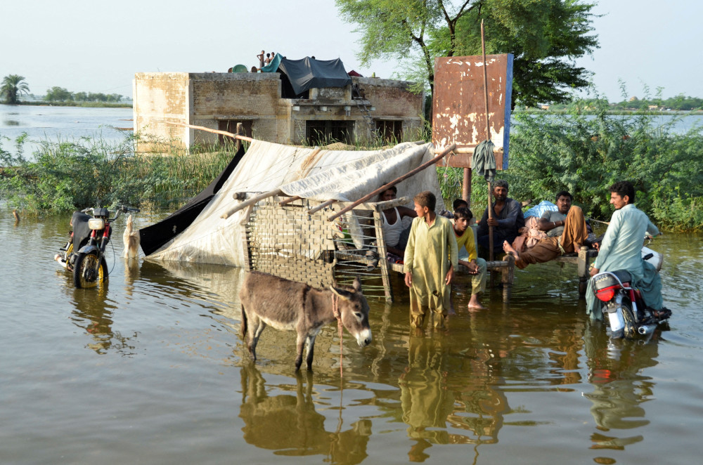 People wade in floodwaters outside their home, following heavy rains during the monsoon season in Sohbatpur district of Pakistan, Aug. 28, 2022. 