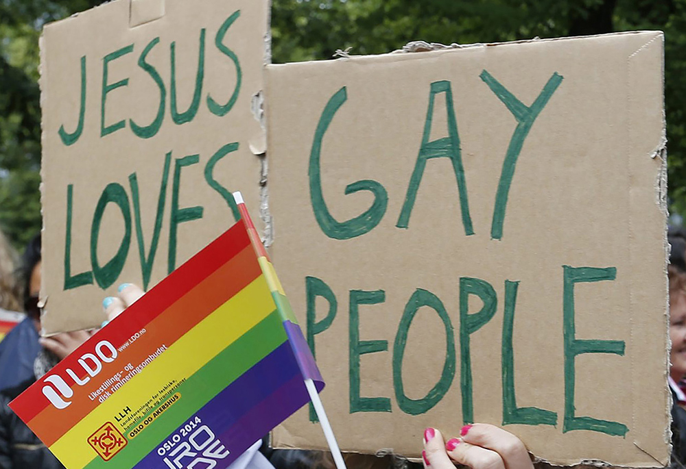 People hold a rainbow flag and signs during a 2014 gay pride parade in Oslo, Norway. In Zambia, some LGBTQ+ Catholics said a church campaign against homosexuality has made them feel unsafe. (CNS/Terje Bendiksby, NTB Scanpix via Reuters)