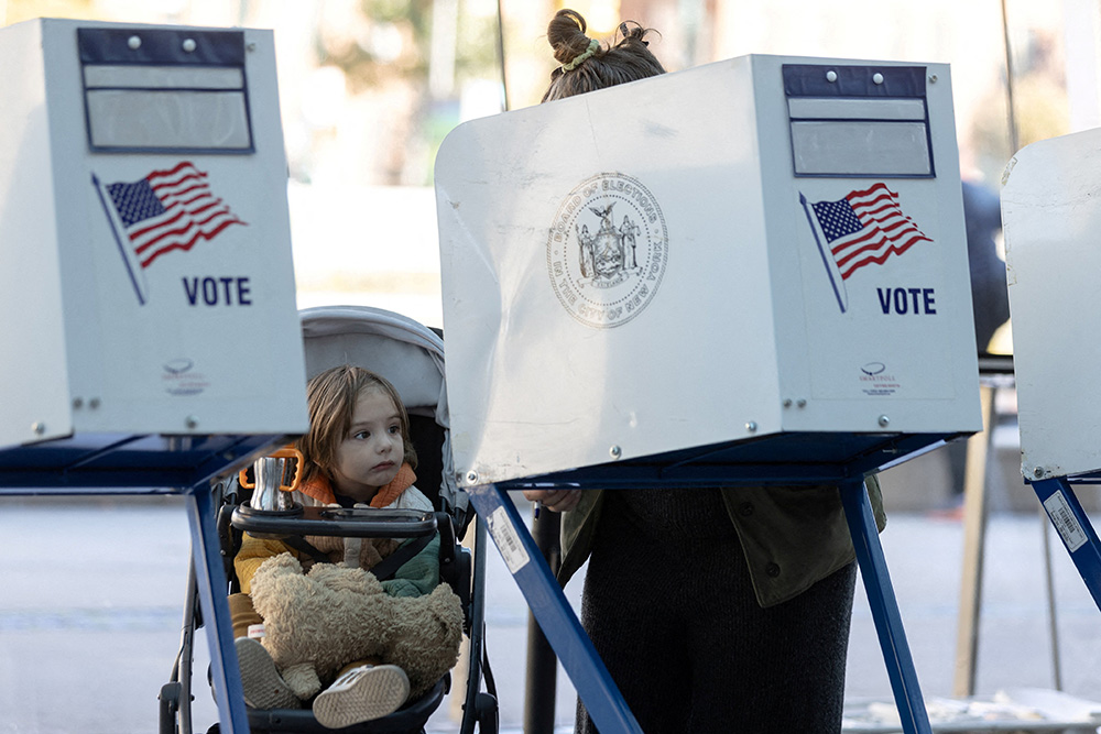 A girl at the Brooklyn Museum in New York City watches her mother cast her ballot during early voting Oct. 29. (CNS/Reuters/Jeenah Moon)