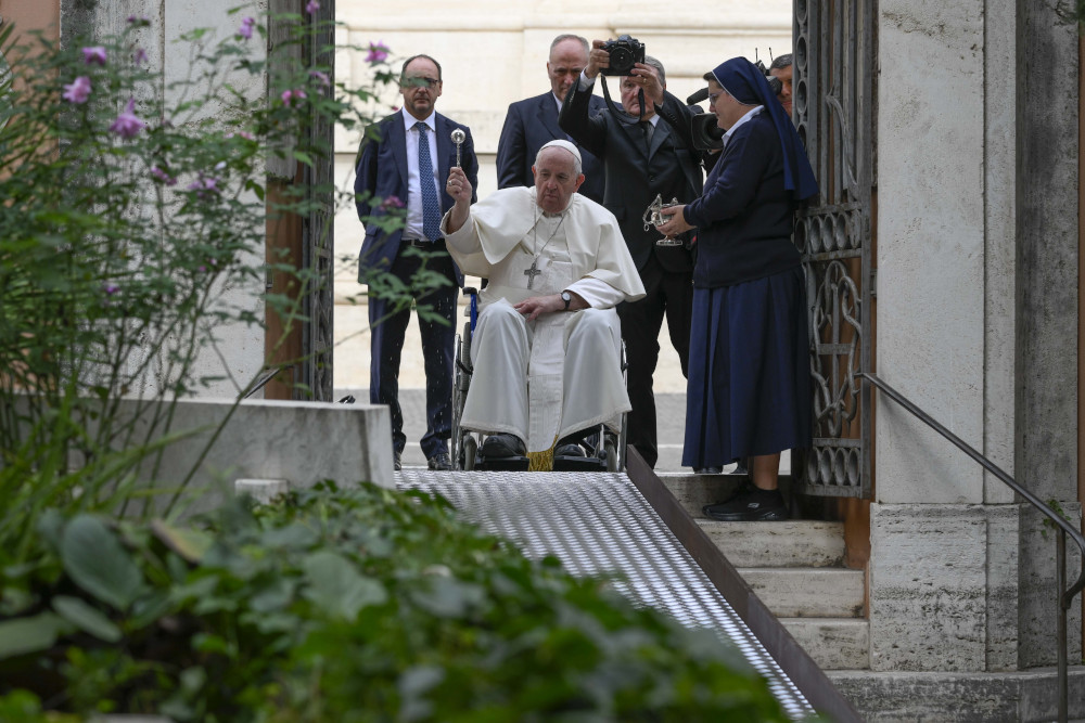 Pope Francis sits in a wheelchair and uses holy water to bless the tombs of those buried in the Vatican's Teutonic Cemetery, a medieval cemetery now reserved mainly for German-speaking priests and members of religious orders, during a visit Nov. 2, 2022, the feast of All Souls. 