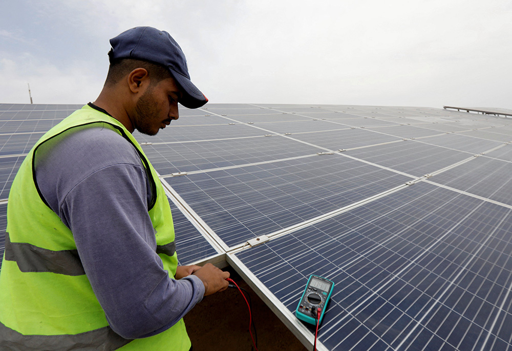 A worker checks solar cells on the rooftop of a hotel June 4 in Sharm el-Sheikh, Egypt. The hotel was working to turn to clean energy as the city prepared to host the COP27 summit Nov. 6-18. (CNS/Reuters/Mohamed Abd El Ghany)