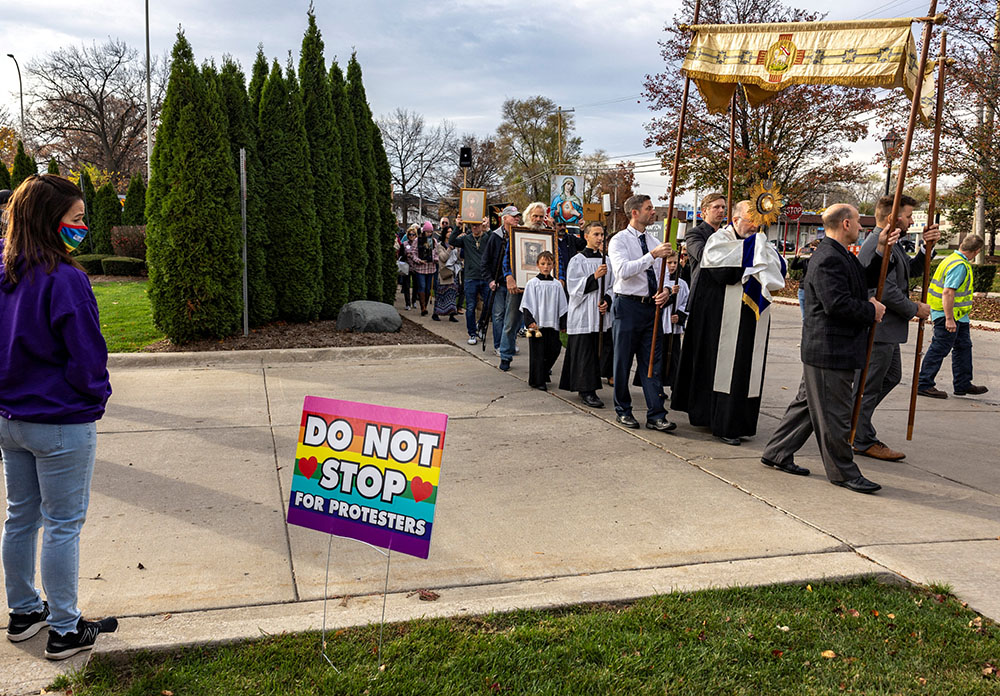 An abortion clinic escort watches a Catholic procession pass Northland Family Planning in Westland, Michigan, Nov. 5, 2022, to demonstrate against a ballot measure known as Proposal 3, which would codify a right to abortion. Michigan voters approved the measure in the Nov. 8 midterm election. (CNS/Reuters/Evelyn Hockstein)