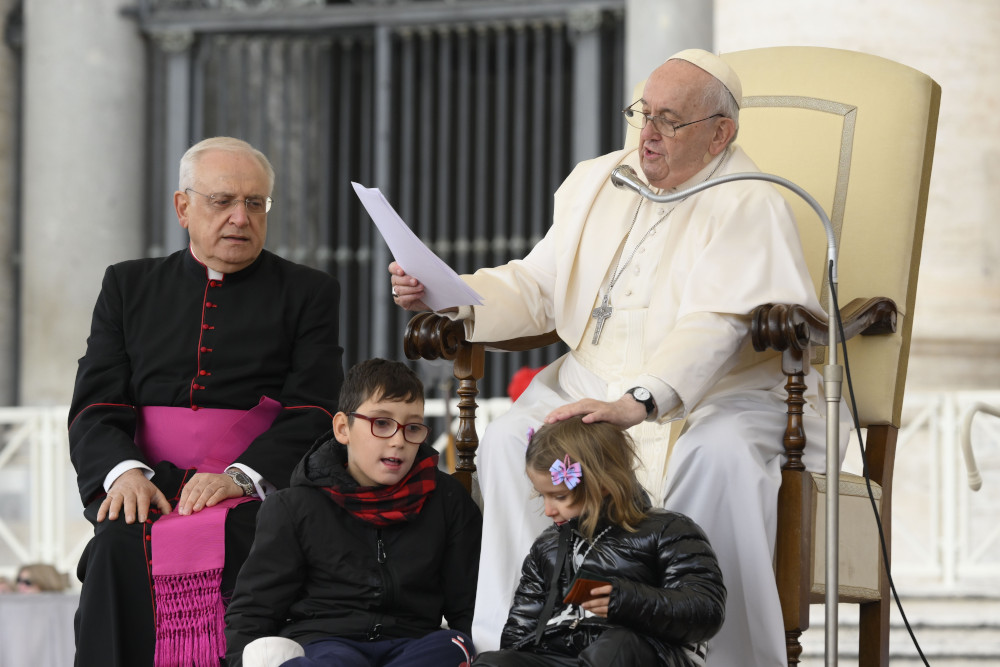 Pope Francis pats the head of a girl after she and another child ran up on to the stage during his weekly general audience in St. Peter's Square Nov. 9, 2022.