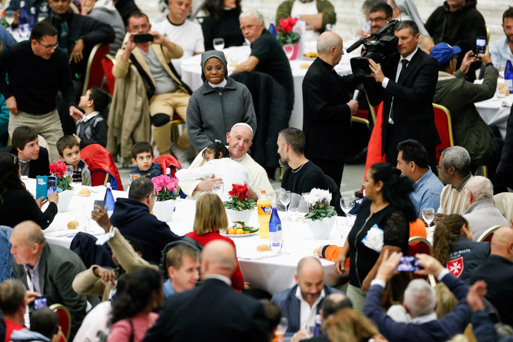 A little girl hugs Pope Francis, as he joins some 1,300 guests for lunch in the Vatican audience hall on the World Day of the Poor Nov. 13, 2022.