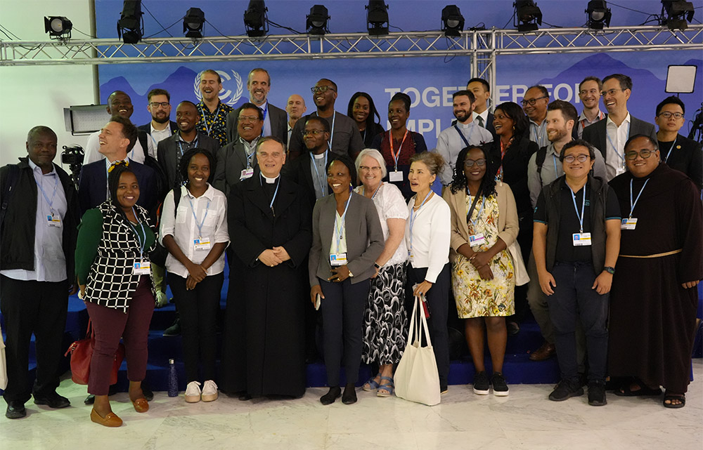 The apostolic nuncio to Egypt, Archbishop Nicolas Thévenin (front row, third from left), who is the deputy leader of the Holy See delegation to COP27, poses for a group photo with Catholics at the U.N. climate conference. The Catholic groups present included the Catholic Youth Network for Environmental Sustainability in Africa, the Laudato Si' Movement and International Alliance of Catholic Development Agencies. (EarthBeat photo/Doreen Ajiambo)