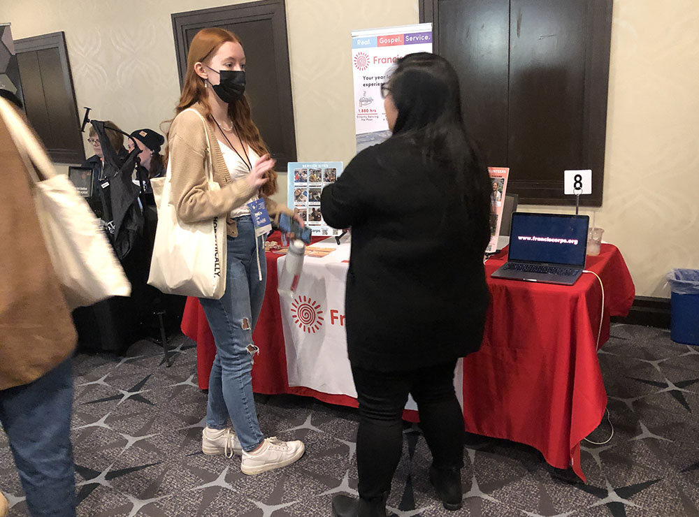 Jenny Rose Anacan, associate director of FrancisCorps, talks with Isabelle Marinchik at the FrancisCorps table at the Ignatian Family Teach-In for Justice in Washington, D.C., Oct. 23. (NCR photo/Aleja Hertzler-McCain)