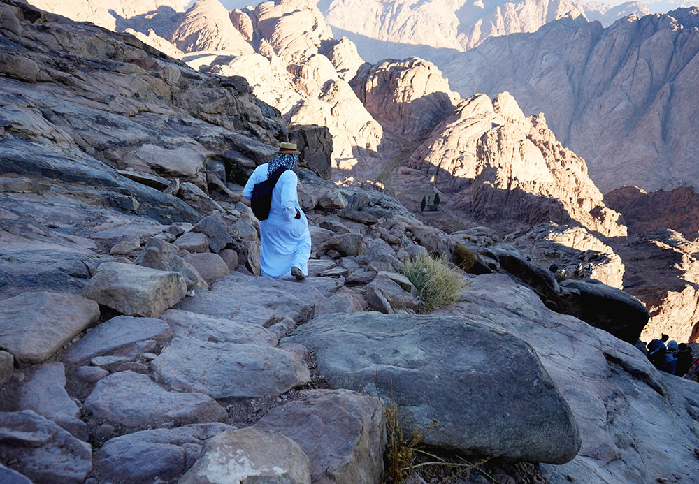 A religious leader climbs down Mount Sinai after watching the sunrise Nov. 14. At the foot of the mountain, he joined climate activists to pray for world leaders to change their hearts and save the planet from damage. (EarthBeat photo/Doreen Ajiambo)